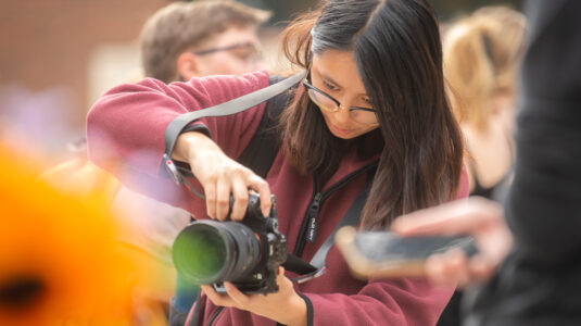 student holds camera to take photo