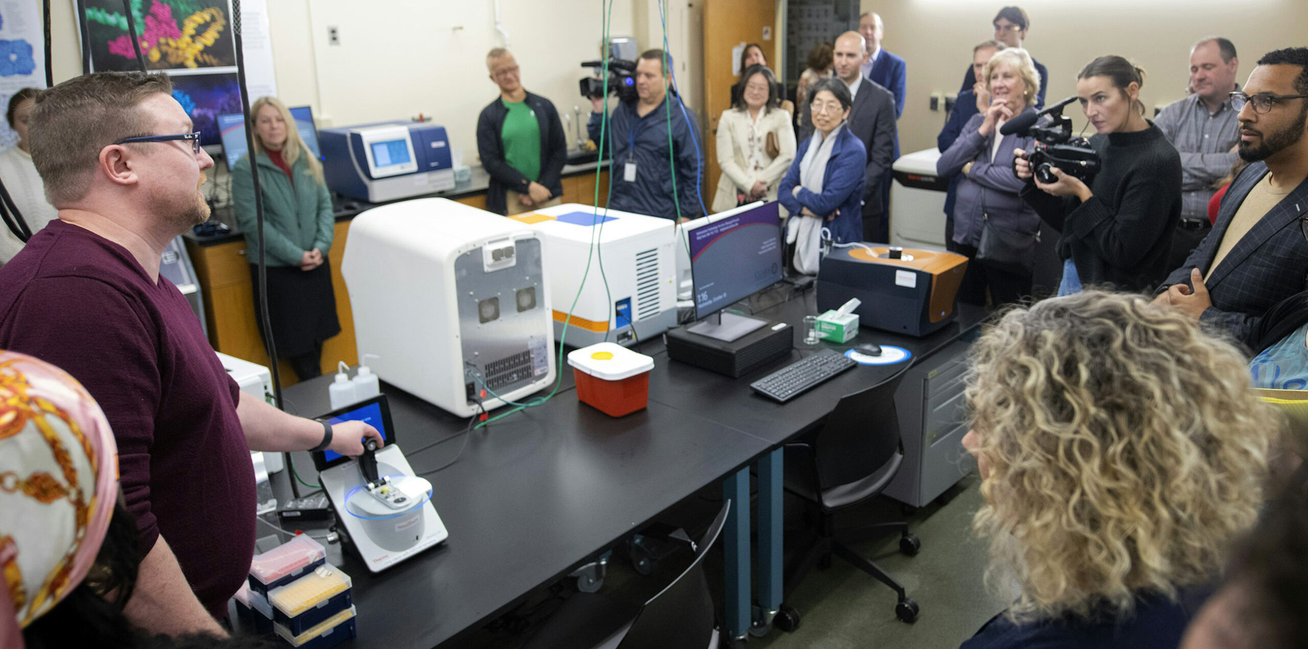 People listening to Professor Donald Spratt as he shows equipment in the new lab