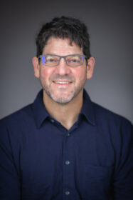 headshot of smiling professor in blue button down shirt