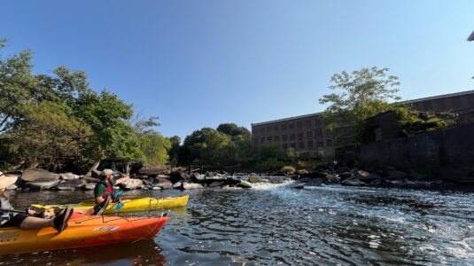 kayakers in water near old mill