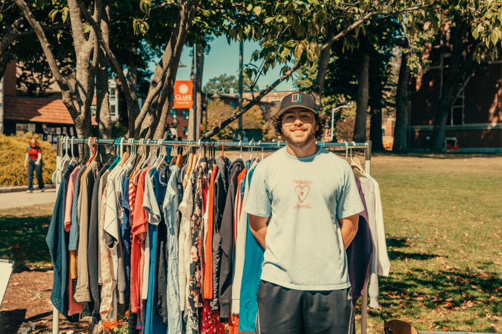 student poses with rack of clothes outside