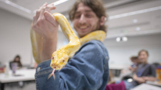 student holds yellow snake