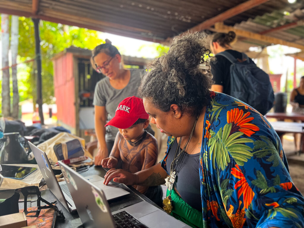 Florencia Sangermano and a child and adult from a local community working on a computer