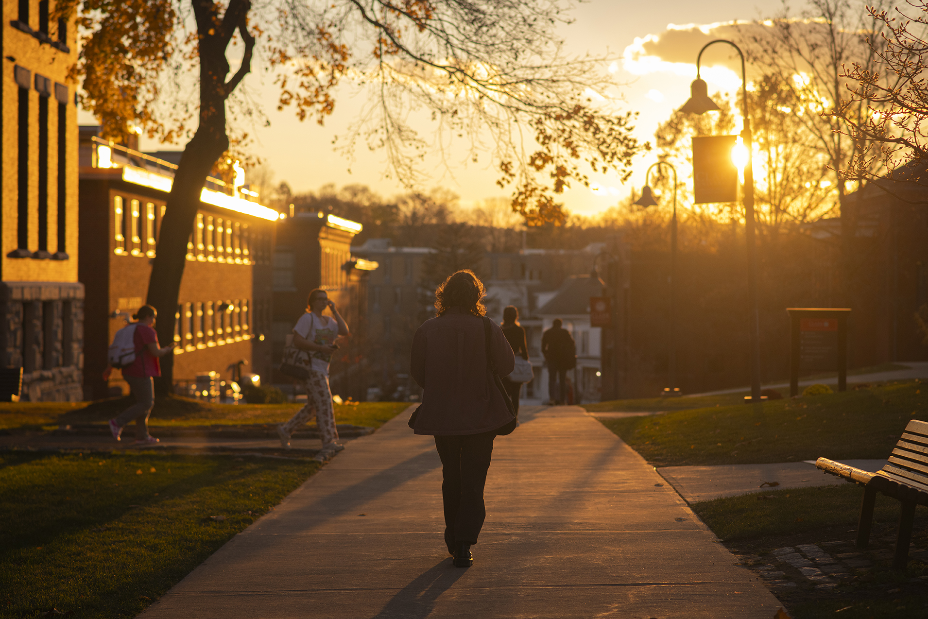 Clark student walking behind Jonas Clark Hall at sunset