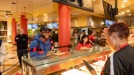 faculty serve students in the dining hall during late-night breakfast