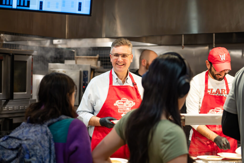 faculty serve students in the dining hall during late-night breakfast