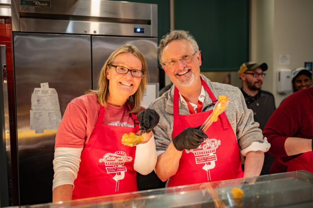 faculty serve students in the dining hall during late-night breakfast