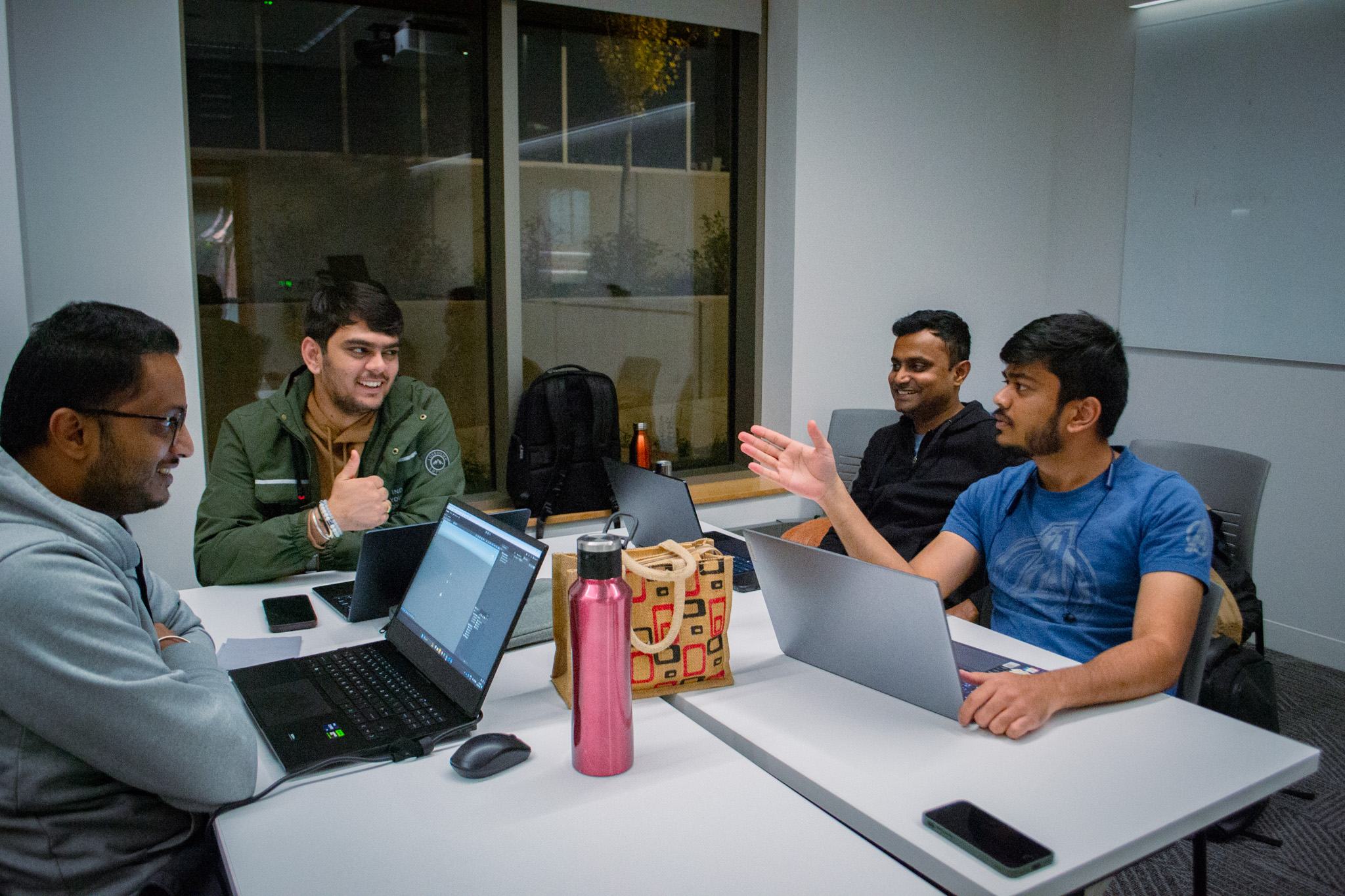 four students sitting at table with laptops