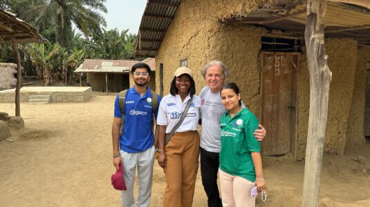 four people pose for photo outside