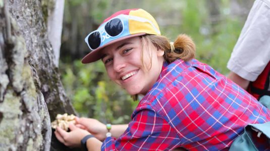 Devon Rose Leaver holding mushroom on a tree